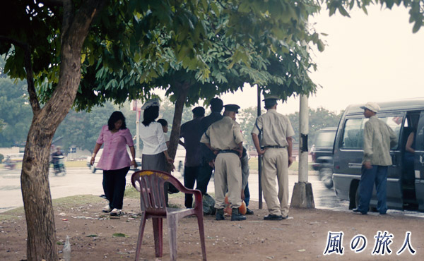カンボジア　老ロ脇の木の下で雨宿りする写真